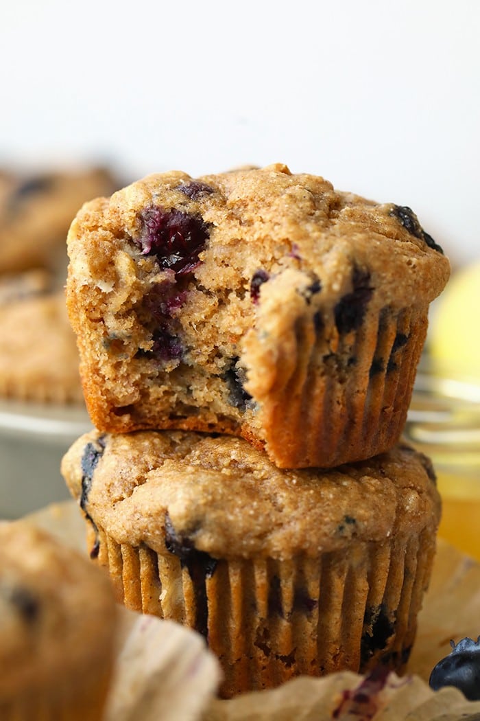 Everyone loves a classic blueberry muffin! These healthy blueberry muffins are packed with tart blueberries, honey, bananas, and greek yogurt! They are healthy and delicious! a blueberry muffin with a bite taken out
