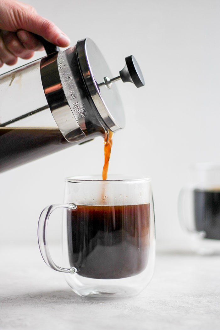 Pouring coffee from a french press into a mug