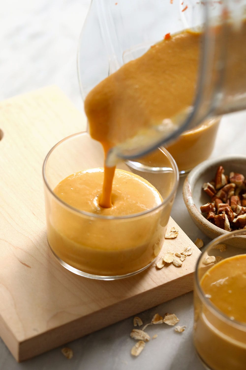 Pouring carrot cake smoothie into a glass.