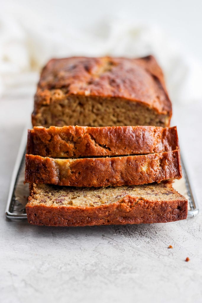 Delicious, airy, moist healthy banana bread coming right up! Our signature healthy banana bread recipe is made with white whole wheat flour, ripe bananas, all-natural sweeteners, and coconut oil. sliced banana bread on cooling rack