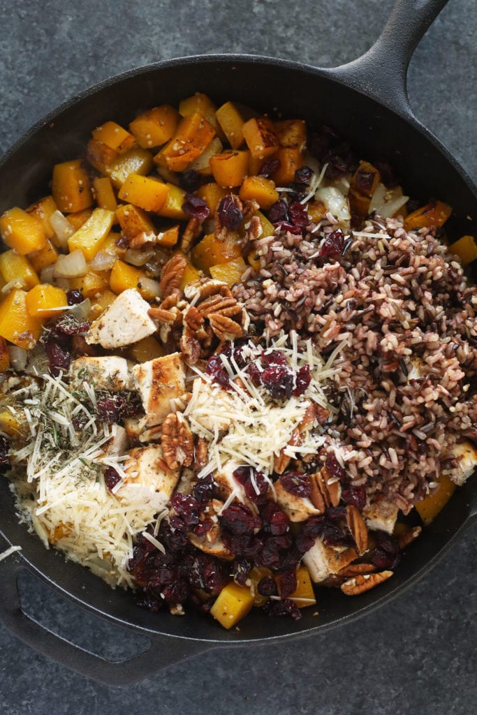 Straight from The Well Plated Cookbook, this Butternut Squash Wild Rice Casserole is the ultimate Fall dish! butternut squash wild rice casserole in a cast iron pan ready to be mixed together and baked