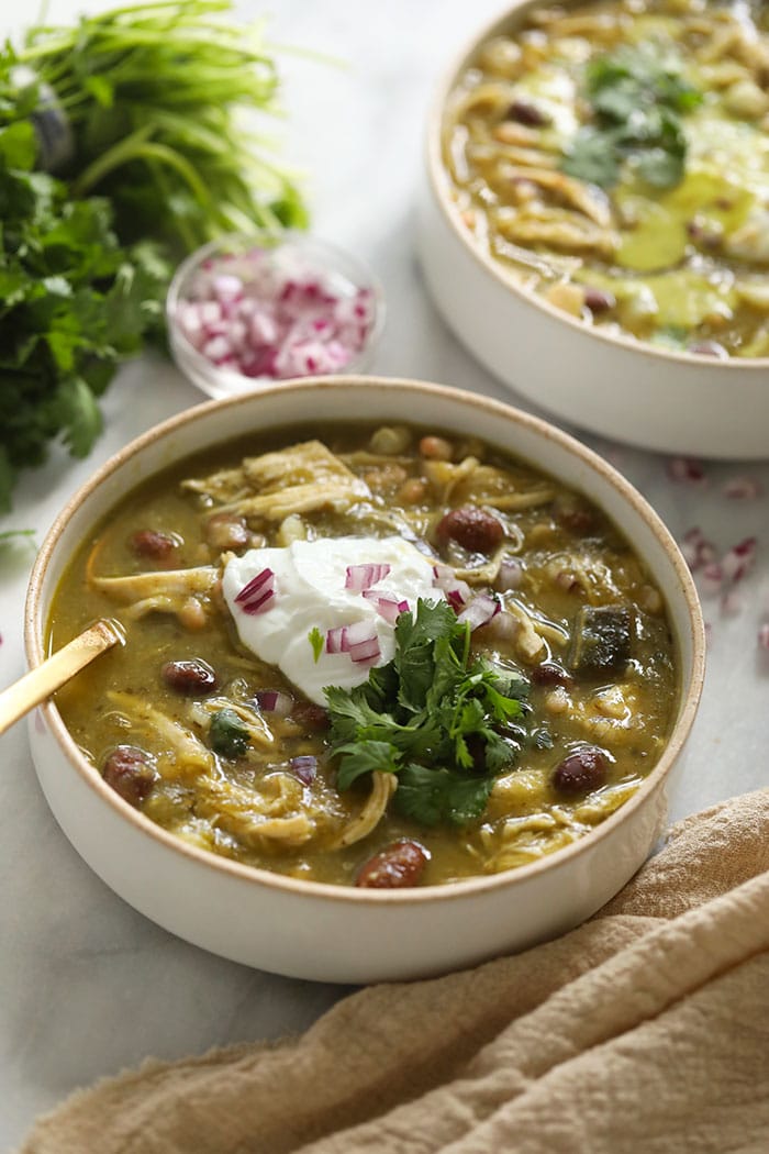 Green Chili (AKA Chile Verde) never looked so good! This easy green chicken chili is made with roasted peppers, your favorite salsa verde, chicken breast, and white beans. green chili in bowl with Greek yogurt