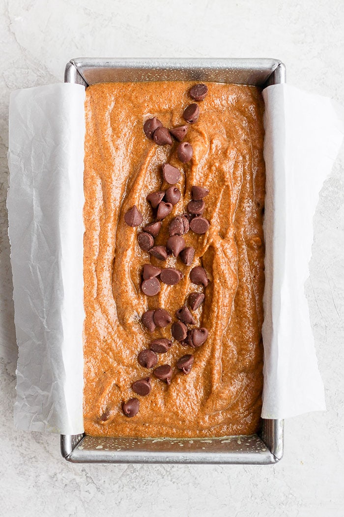 It’s pumpkin season! Which means it’s time to make this moist and flavorful Healthy Pumpkin Bread. Packed with pumpkin puree and a few chocolate chips + the just right amount of cinnamon, nutmeg, cloves and ginger, this pumpkin bread is something your whole family will enjoy! healthy pumpkin bread in a loaf pan ready to be baked