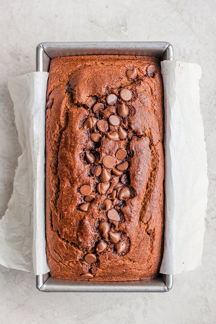 It’s pumpkin season! Which means it’s time to make this moist and flavorful Healthy Pumpkin Bread. Packed with pumpkin puree and a few chocolate chips + the just right amount of cinnamon, nutmeg, cloves and ginger, this pumpkin bread is something your whole family will enjoy! healthy pumpkin bread loaf just out of the oven looking delicious