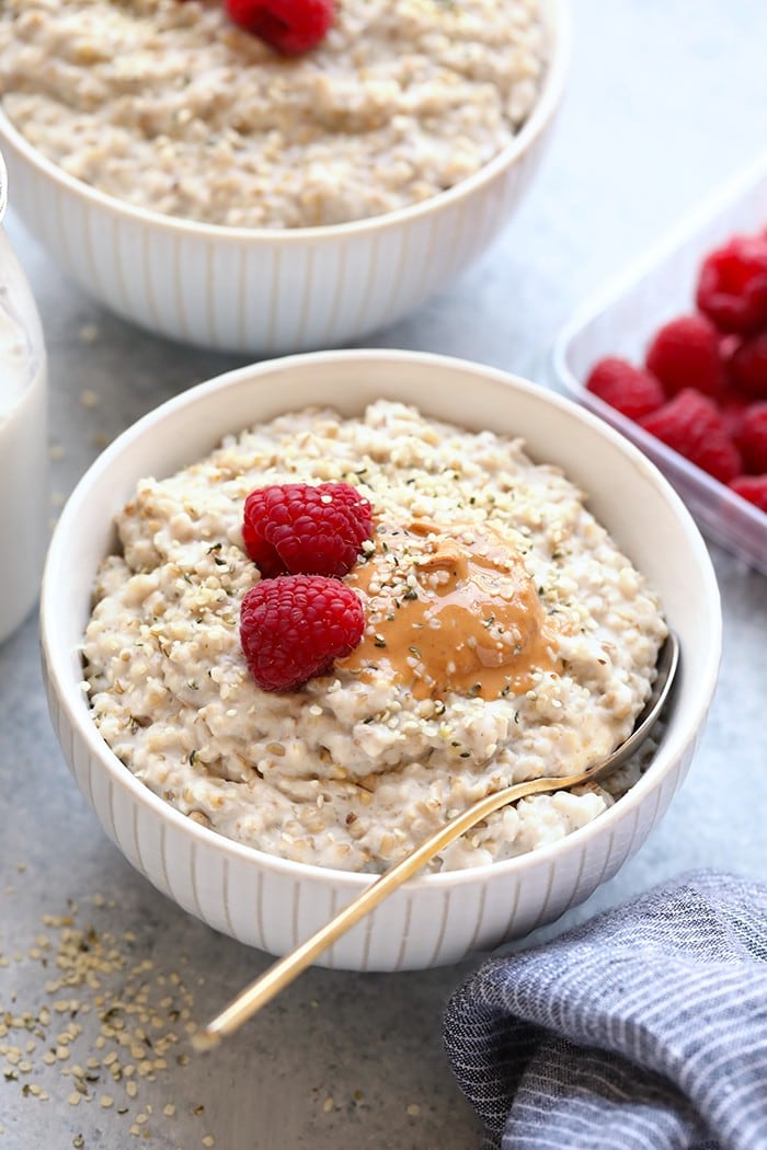 Make these Instant Pot Steel Cut Oats in a fraction of the time. They're creamy, served hot, and naturally gluten-free and vegan! steel cut oats in bowl with nut butter and raspberries