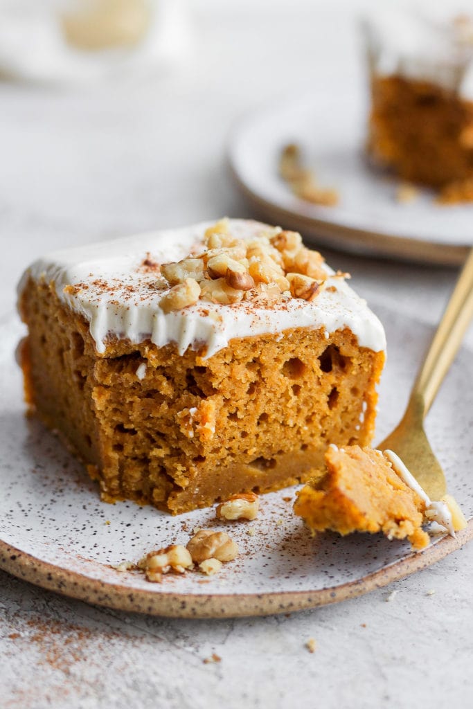 This pumpkin sheet cake is as easy as it is delicious. Packed with simple ingredients and topped with a yummy cream cheese frosting, this dessert can't be beat! slice of pumpkin sheet cake on a plate with a bite ready to eat on a fork