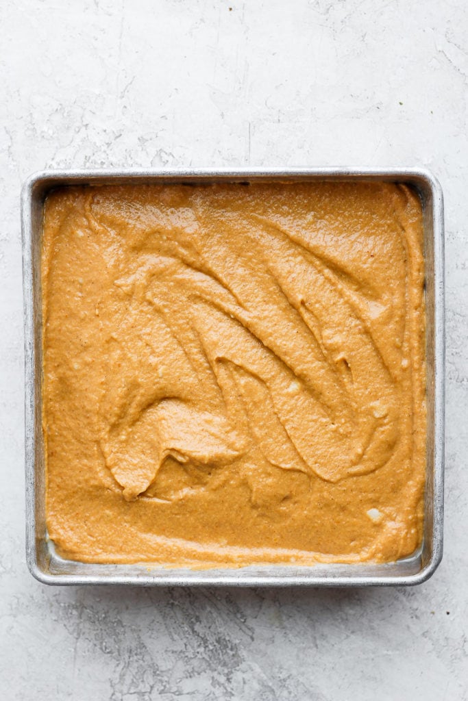 This pumpkin sheet cake is as easy as it is delicious. Packed with simple ingredients and topped with a yummy cream cheese frosting, this dessert can't be beat! pumpkin sheet cake batter in a square pan
