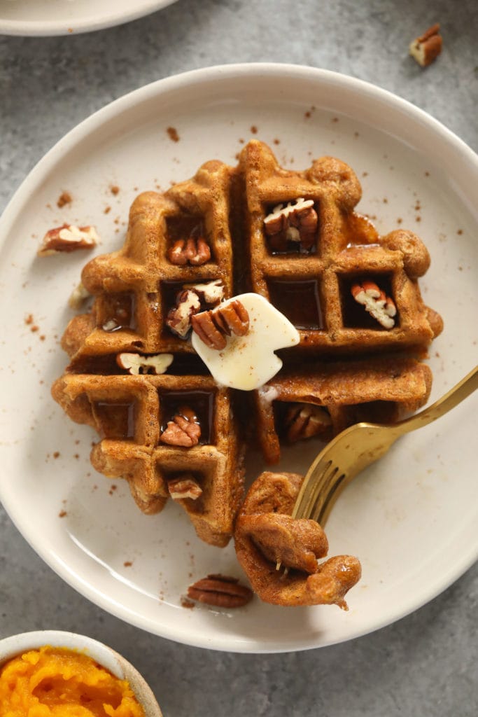 Got pumpkin? Make these delicious, fool-proof gluten-free pumpkin waffles! They're made with no refined sugar, no dairy, and just a small amount of coconut oil. This is a recipe the entire family will love. pumpkin waffle on plate with fork