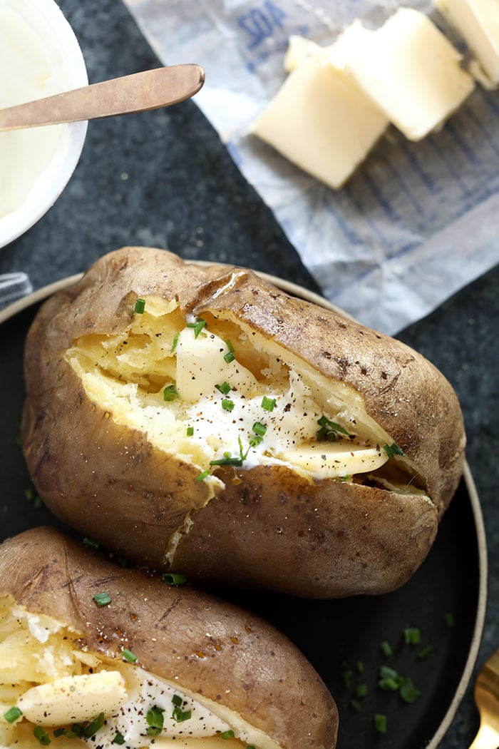 The easiest way to make perfect baked potatoes is in the crock pot! These Crock Pot Baked Potatoes are truly a set it and forget it recipe, leaving precious space in your oven to bake other recipes you're making. crock pot baked potatoes topped with chives and sour cream