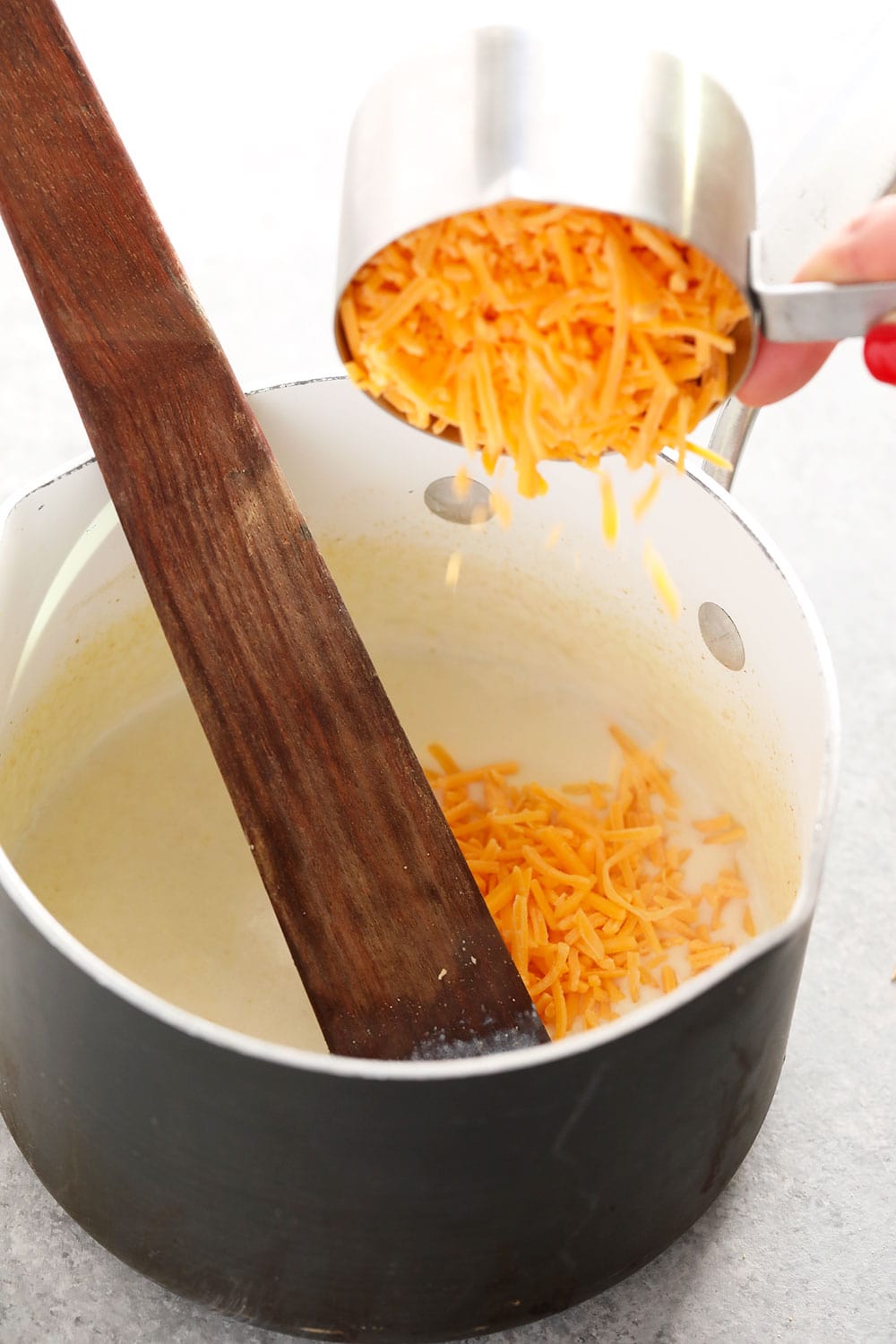 This Three Cheese Cauliflower Mac and Cheese is keto, low carb, and oh so delicious! And did we mention it packs 20g of protein? Yah welcome. cauliflower mac and cheese sauce being mixed in a pot