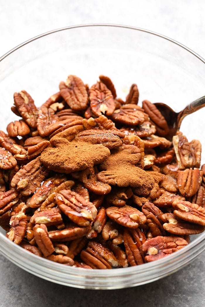 There's nothing better than sweet roasted pecans on a fall salad. Make these Oil-Free Maple Roasted Pecans in 10 minutes! Maple roasted pecans with cinnamon in a mixing bowl.