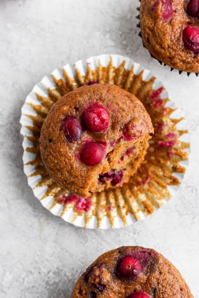 These Cranberry Orange Muffins are bursting with all those seasonal flavors you love! Made from healthy ingredients, including fresh cranberries and orange zest. Enjoy! cranberry orange muffin in a muffin liner