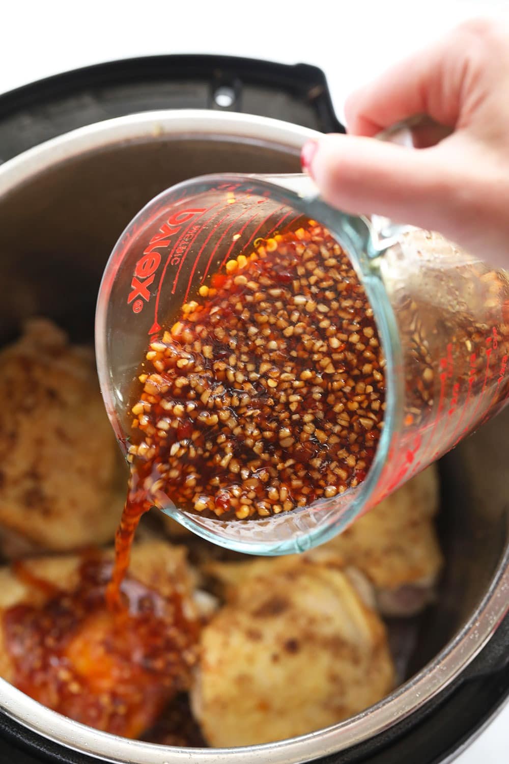 The best honey garlic chicken thighs made in the Instant Pot in under 30 minutes! honey garlic sauce in jar