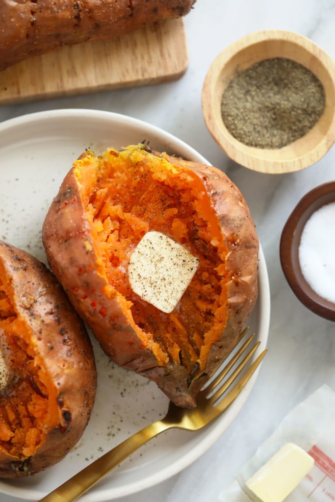 Baked sweet potatoes are a delicious addition to any meal. In this post, we'll teach you how to bake sweet potatoes in 3 easy steps and how to flavor and re-purpose your oven baked sweet potatoes! baked sweet potato recipe on plate with butter