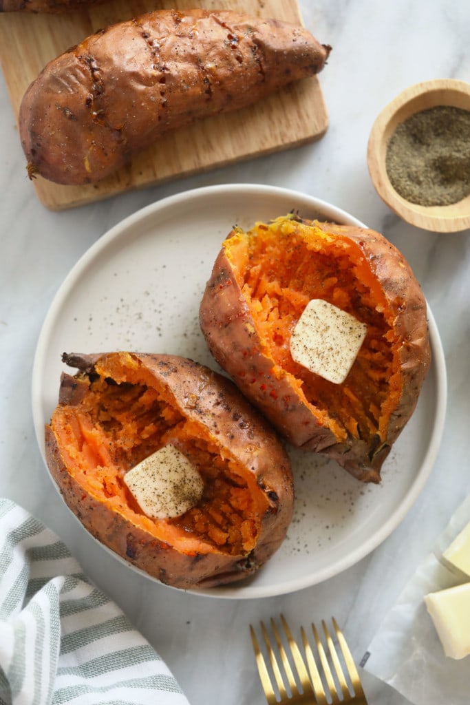 Baked sweet potatoes are a delicious addition to any meal. In this post, we'll teach you how to bake sweet potatoes in 3 easy steps and how to flavor and re-purpose your oven baked sweet potatoes! 2 sweet potatoes on plate with butter and pepper