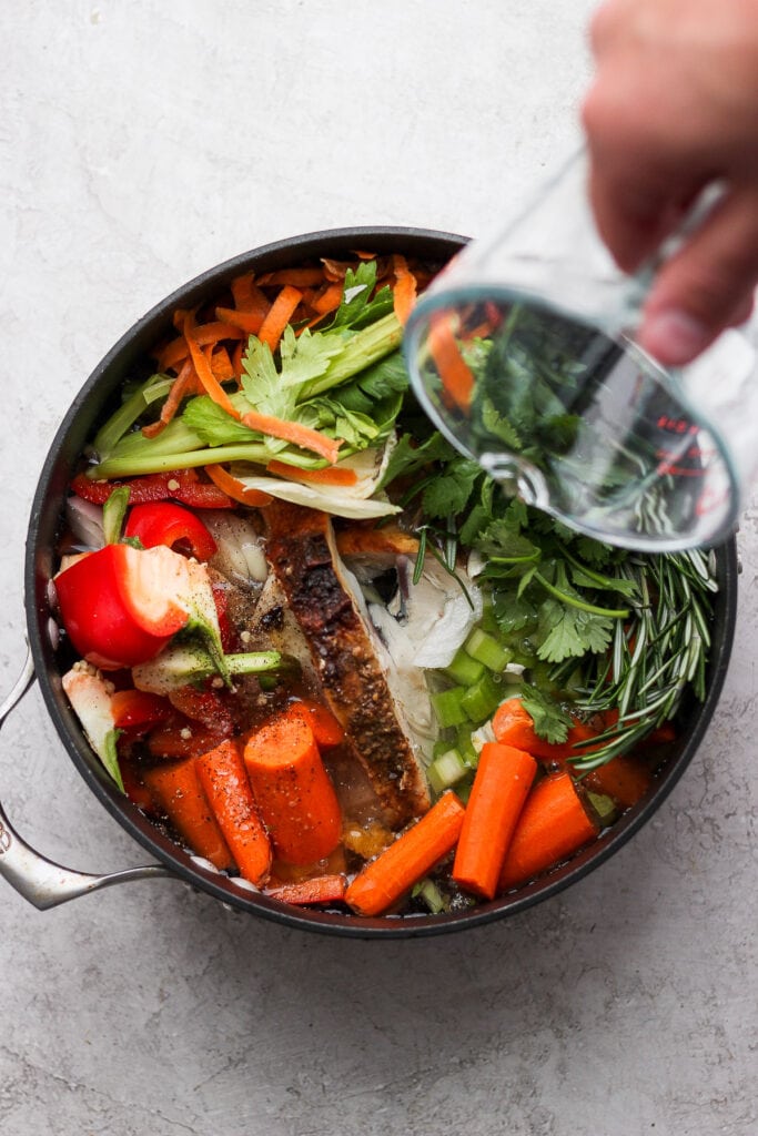 Pouring water into a pot full of vegetables.