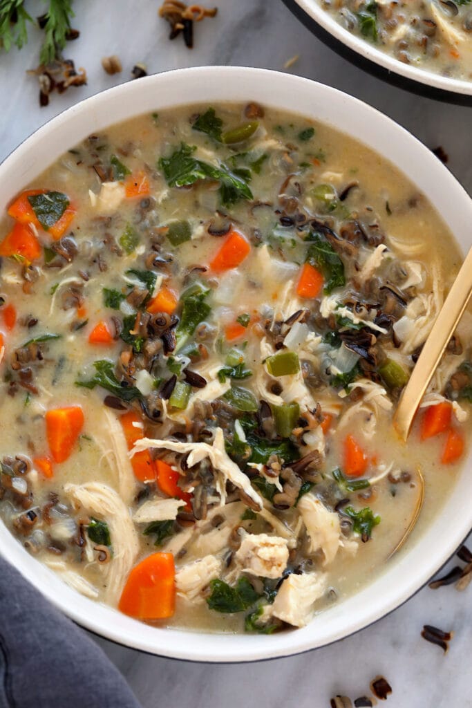 This cozy stovetop Chicken Wild Rice Soup is packed with healthy veggies and made creamy with a delicious roux. Make a large batch and enjoy it throughout the week! chicken wild rice soup in a bowl ready to be enjoyed