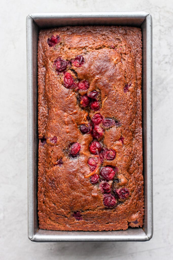 This seriously moist Cranberry Orange Bread is flavor-packed with fresh cranberries and orange zest, and finished with a delicious cream cheese glaze. cranberry orange bread after its been baked in a loaf pan