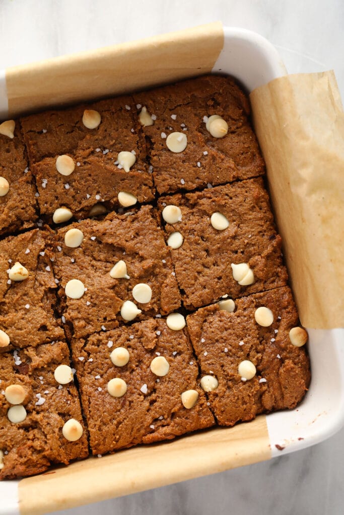 These Gingerbread Cookie Bars are the perfect festive sweet treat! Whip up a batch, and you'll be biting into these deliciously chewy bars in under an hour. Enjoy! gingerbread cookie bars in a baking dish cut into square bars