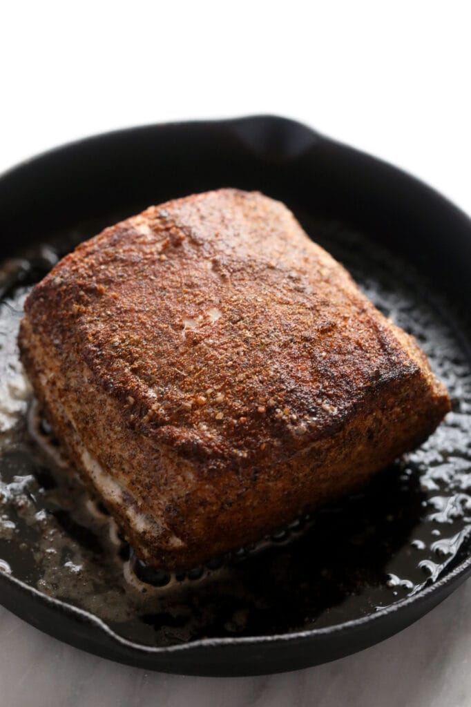 This is the most tender Slow Cooker Pork Loin roast recipe ever! It's served with potatoes and a savory gravy for the perfect meal. Enjoy! slow cooker pork loin being seared in a cast iron skillet