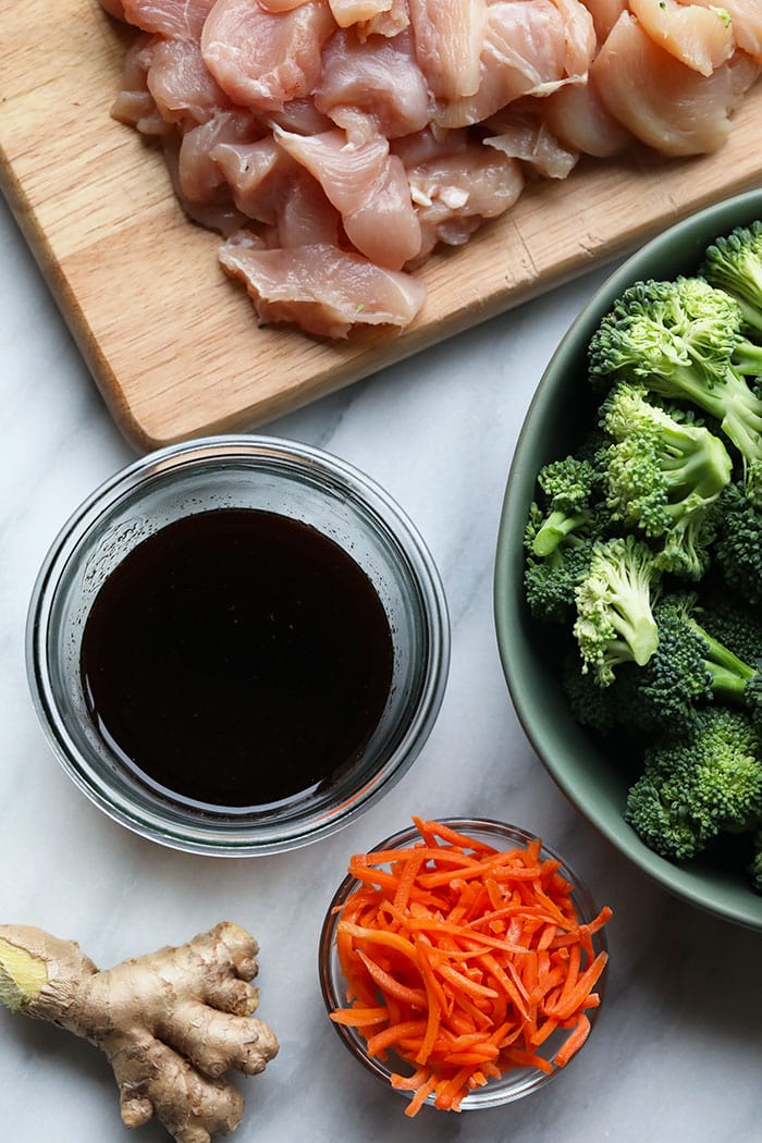 This chicken stir fry recipe is made with chicken breast, broccoli, and carrots, and the sauce is made with fresh ginger, soy sauce/tamari, honey, and sriracha. ginger, soy sauce, broccoli, carrots, and chicken breast in bowls