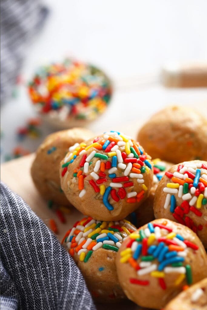 These super flavorful Cake Batter Protein Balls are energy packed from 6 simple ingredients. And no food processor required! cake batter protein balls covered in rainbow sprinkles on a plate