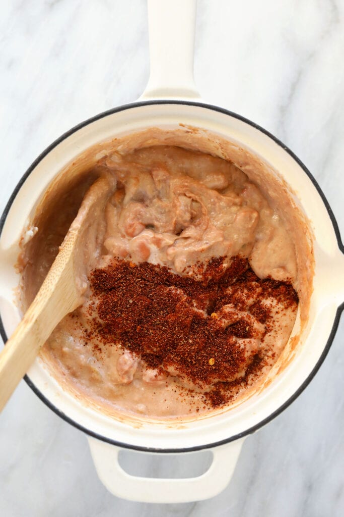 This bean dip makes a perfect appetizer. It's protein-packed from refried and pinto beans, as well as Greek yogurt and cheddar cheese. It truly is the best! bean dip ingredients being mixed together in a skillet