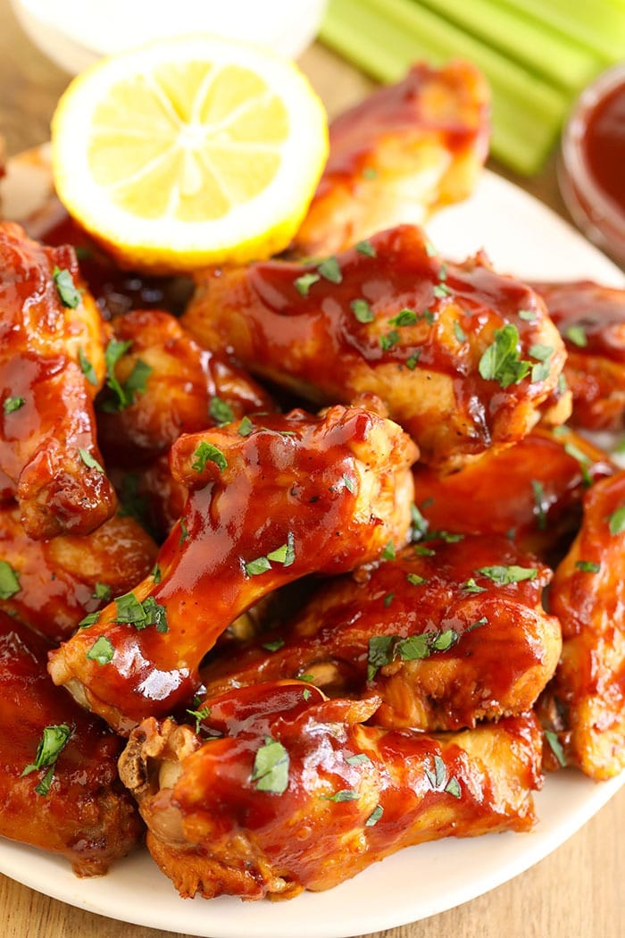 Love chicken wings, but don't want to heat up your whole house? Make our amazing Crockpot Chicken Wings for your next appetizer or snack. Bonus, these crockpot bbq chicken wings aren't fried, so they're on the healthier side! bbq wings on a plate with lemon