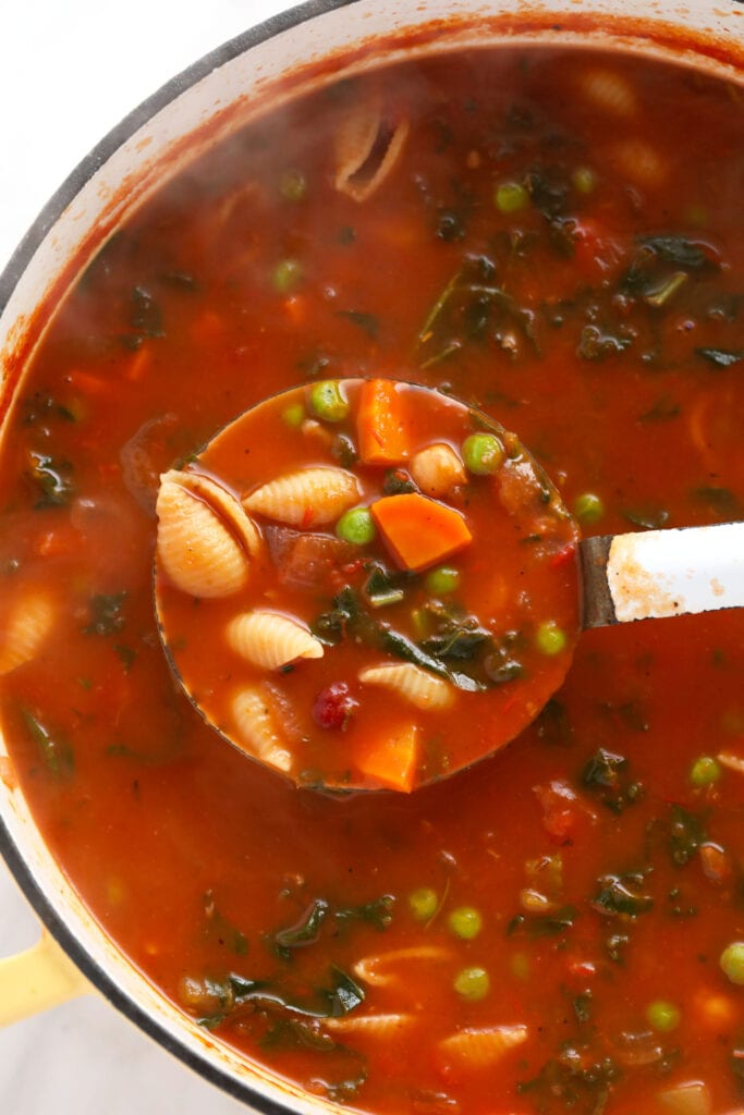 A ladle full of minestrone soup.