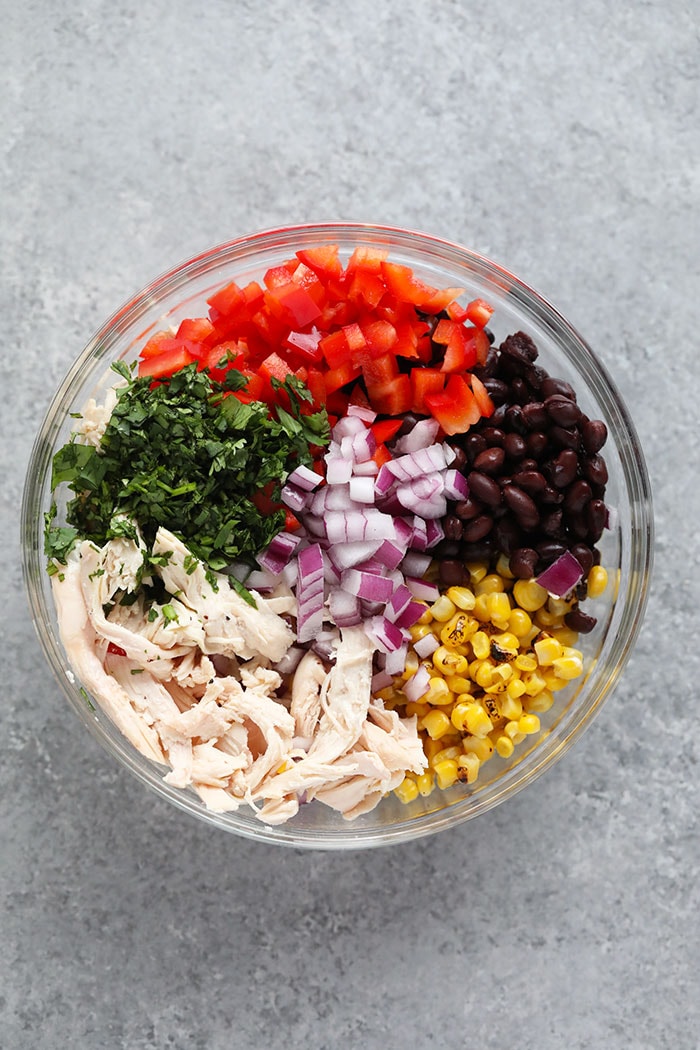 Lunch never tasted so good! Make our Southwest Chicken Salad for a colorful, veggie-packed lunch/dinner idea to keep you full all week long. ingredients in a glass bowl of southwest salad