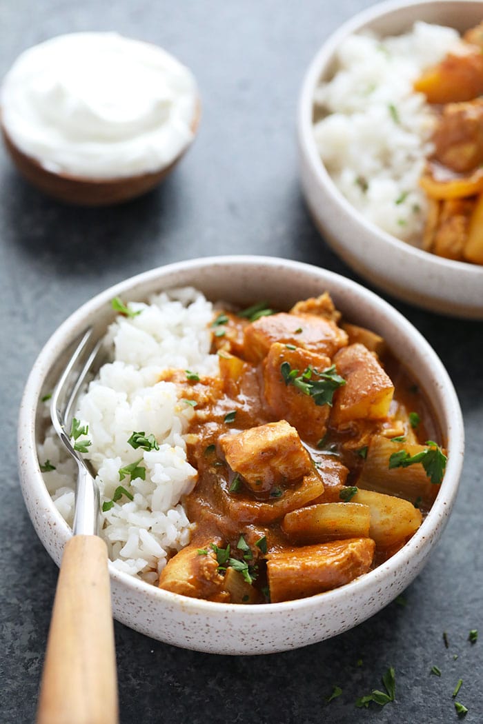This Healthy Slow Cooker Chicken Tikka Masala is savory, hearty and made completely in the slow cooker. Prep a batch and you'll have dinner in no time, or meal prep and freeze for the perfect freezer meal at a later date. Healthy slow cooker meals have never been easier! slow cooker chicken tikka masala in a bowl with rice