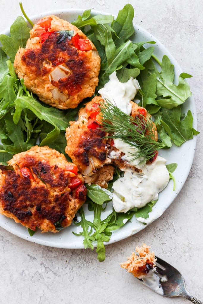 Got leftover salmon to use up? Make these super easy and delicious salmon patties for the perfect leftover meal today! salmon patties on a plate atop arugula
