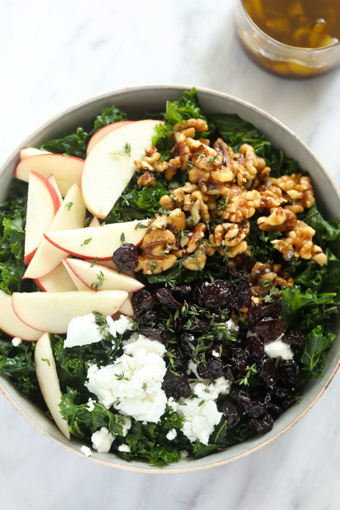 Looking for a last-minute Thanksgiving salad idea? Try our delicious massaged kale, apple, and walnut salad made with goat cheese, dried cherries, and our favorite vinaigrette! Thanksgiving salad in bowl with apples