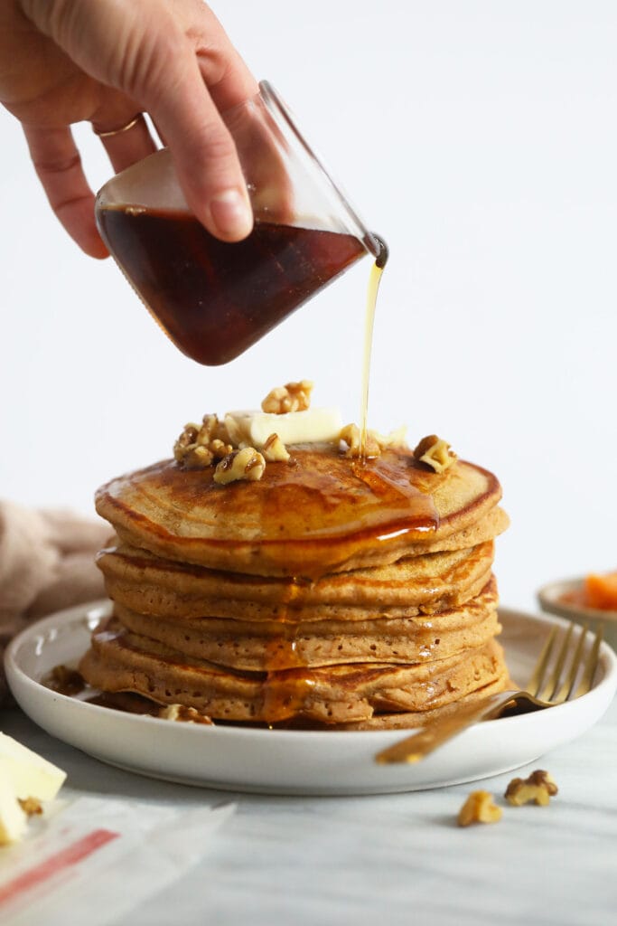 Pouring maple syrup over sweet potato pancakes.