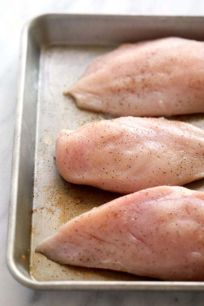 Wondering how to make the easiest shredded chicken? Look no further! This shredded chicken is baked to perfection, and will easily become a meal-prep staple in your home. raw chicken breasts ready to be baked and then shredded