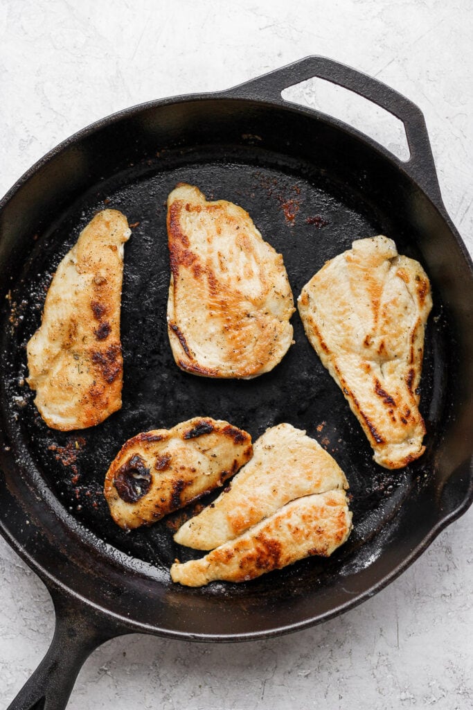 Browning chicken in a cast iron pan.