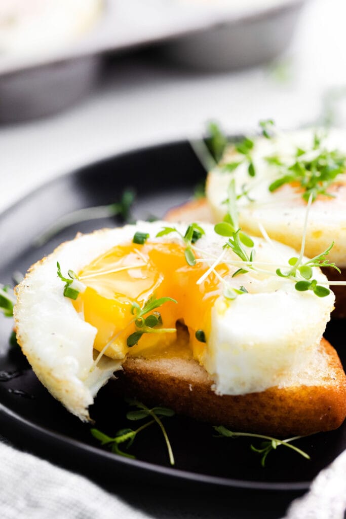 Wondering how to bake eggs in the oven? In this post, we'll teach you how to get perfect baked eggs every time no matter what kind of yolk you like. baked egg with runny yolk on bread