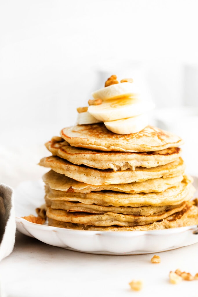 This banana pancake recipe is the ultimate weekend breakfast. Why? These banana pancakes come out super fluffy and they taste heavenly topped with fresh banana and warm maple syrup. stack of pancakes with banana on top
