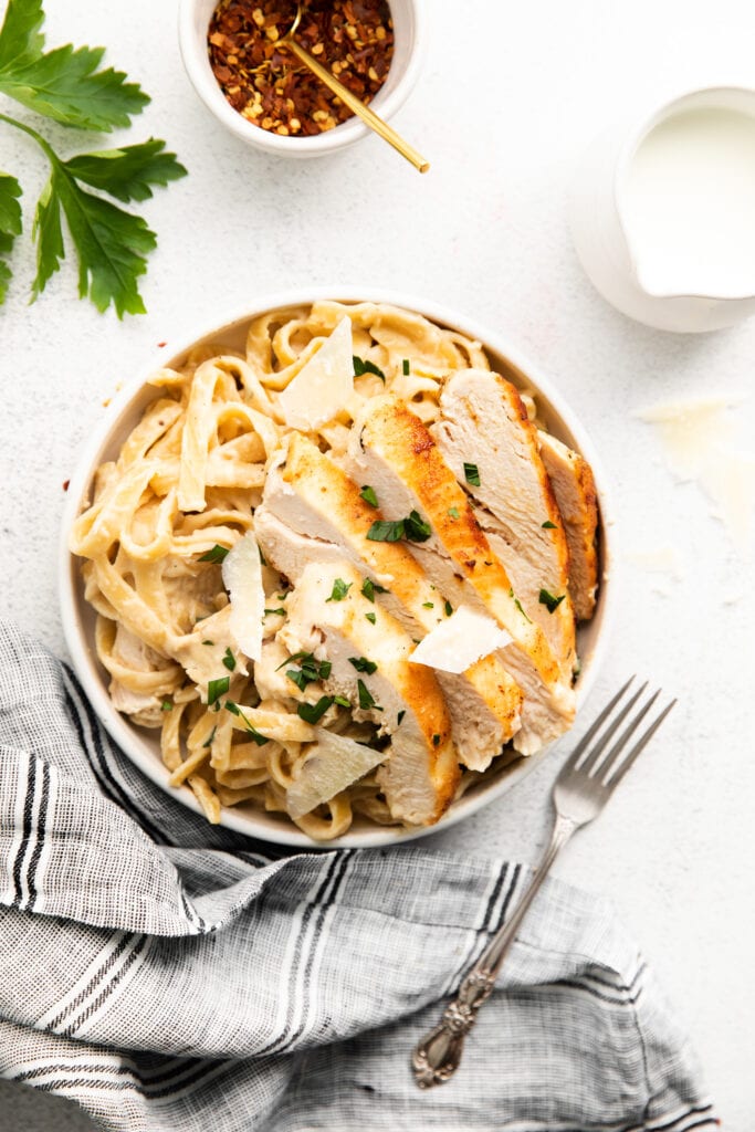 Homemade chicken Alfredo is easier to make than you think. You'll love this silky, flavorful alfredo sauce paired with pan-seared chicken and fettucini! homemade chicken alfredo in bowl
