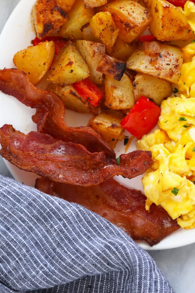 A delicious bacon in air fryer recipe that takes less than 10 minutes and 1 ingredient - BACON! bacon with eggs and potatoes on plate