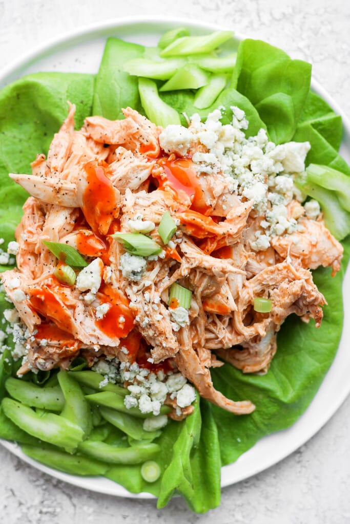 Shredded buffalo chicken in a lettuce wrap with blue cheese, celery, and green onions.