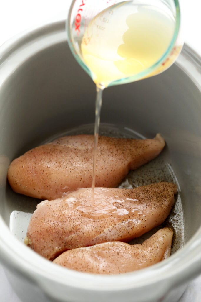 Crockpot shredded chicken is the easiest method for making shredded chicken. It's a set it and forget it kind of shredded chicken that's hands-off and straightforward. raw chicken in slow cooker with chicken broth