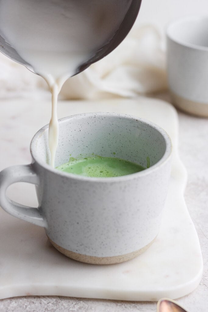 Ready to learn how to make a matcha latte? Matcha green tea lattes are a great substitute for an espresso latte. Keep reading to learn how to perfect this warm, drink! pouring steamed milk on top of matcha powder in mug