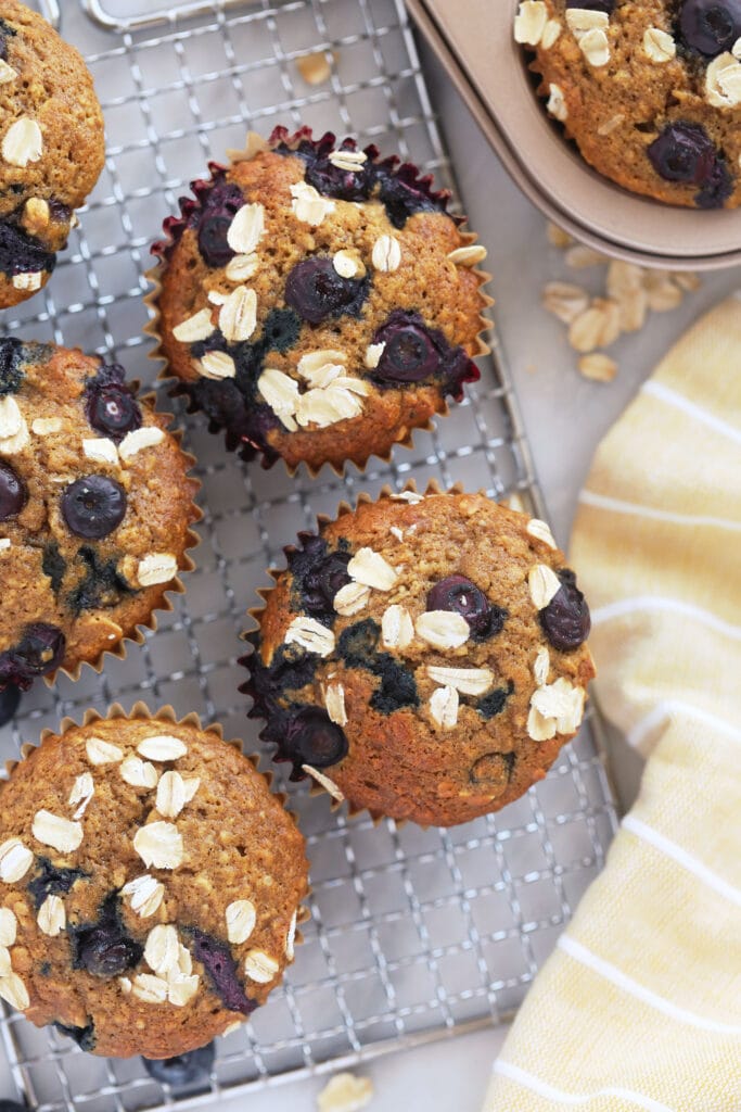 These Blueberry Oatmeal Muffins are super fluffy and made with a short list of healthy ingredients. Plus, they pack 3g of protein per muffin. Enjoy! blueberry oatmeal muffins on a cooling rack looking delicious and fluffy