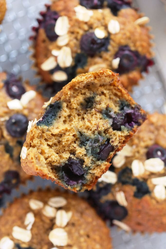 These Blueberry Oatmeal Muffins are super fluffy and made with a short list of healthy ingredients. Plus, they pack 3g of protein per muffin. Enjoy! blueberry oatmeal muffin cut in half looking fluffy and delicious and packed with flavorful blueberries