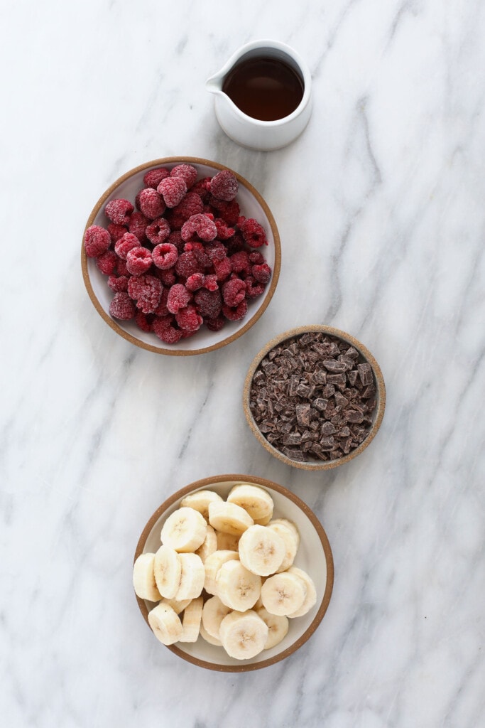 This 5-ingredient Raspberry Chocolate Chunk Nice Cream boasts the same creamy deliciousness of traditional raspberry ice cream, but without all those fillers. ingredients for raspberry chocolate chunk banana nice cream, ready to be added to a food processor