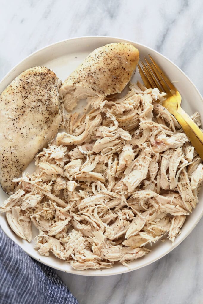 Crockpot shredded chicken is the easiest method for making shredded chicken. It's a set it and forget it kind of recipe great for meal prep. shredded chicken on plate