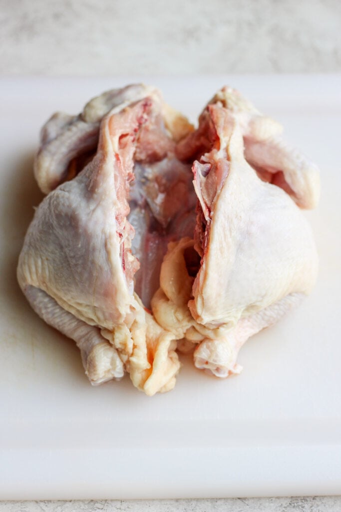 Raw spatchcock chicken on a platter. 