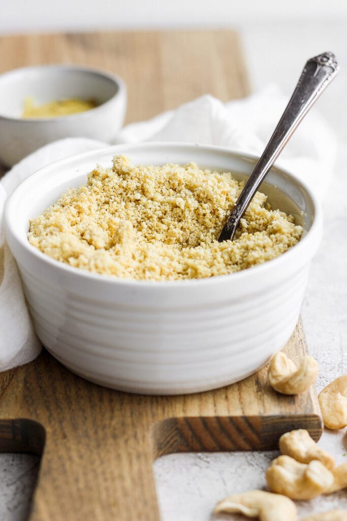 This 5-Ingredient Vegan Parmesan Cheese is a delicious vegan alternative to traditional grated parmesan. Make a batch and sprinkle onto any savory dish your heart desires. vegan parmesan cheese in a bowl with a spoon