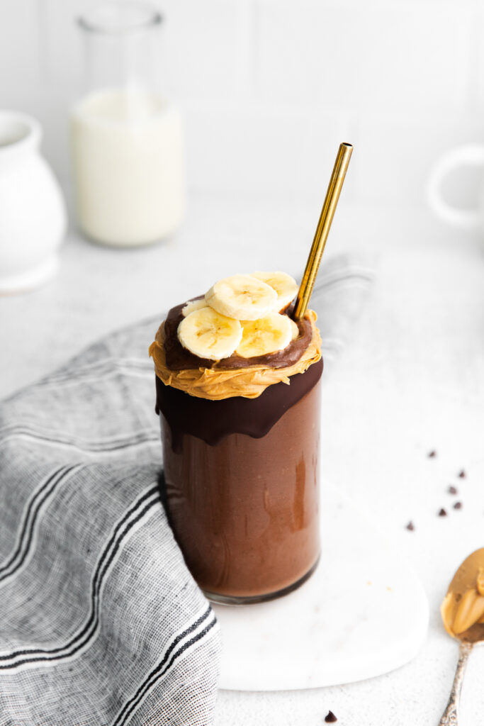 This Chocolate Peanut Butter Banana Smoothie is packed with protein and even has a full serving of greens in it. The best part is, it's healthy and tastes exactly like a peanut butter cup! smoothie topped with peanut butter and banana